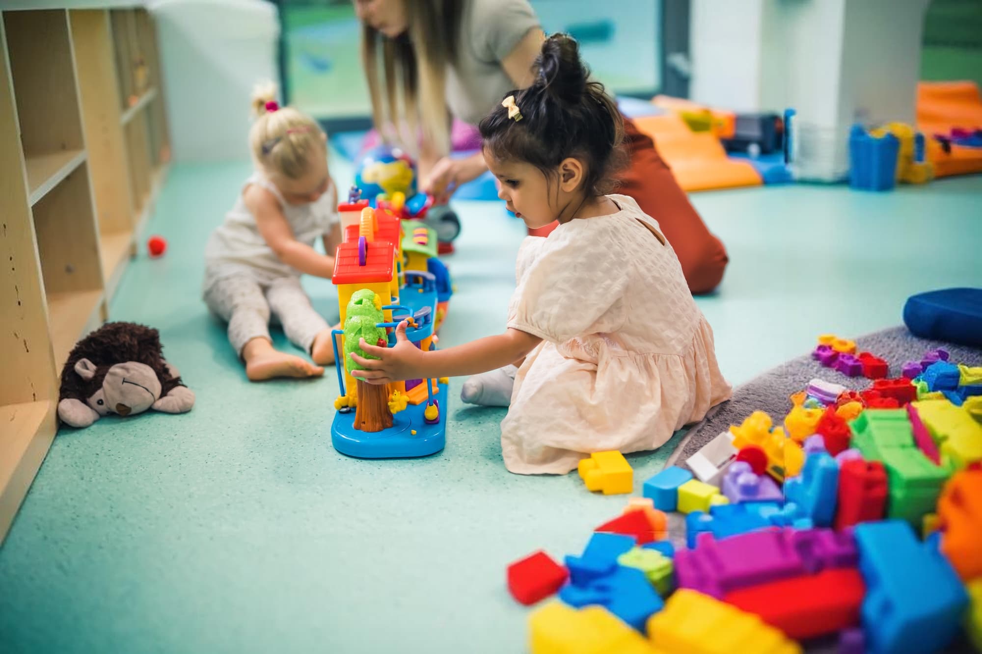 Children playing with toys on the classroom floor at Kids Cove Learning Academy
